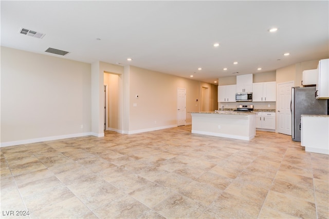 kitchen featuring white cabinetry, appliances with stainless steel finishes, light stone countertops, and a center island with sink