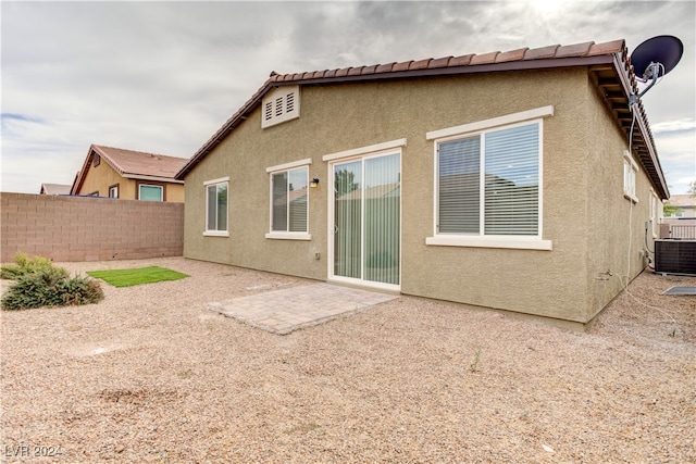 back of property with central AC unit and a patio