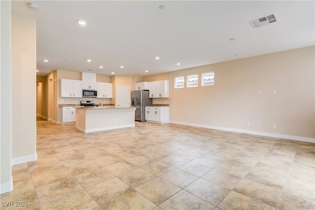 kitchen featuring white cabinetry, light stone countertops, a center island with sink, and stainless steel appliances