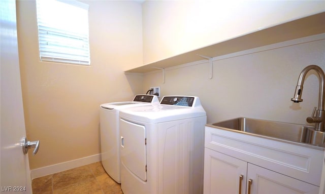 clothes washing area featuring cabinets, sink, and separate washer and dryer