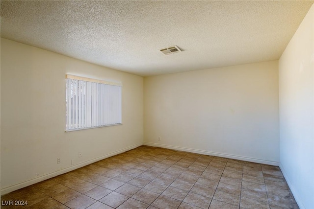 tiled empty room with a textured ceiling