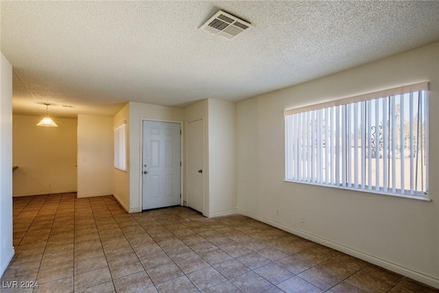 tiled spare room with a textured ceiling