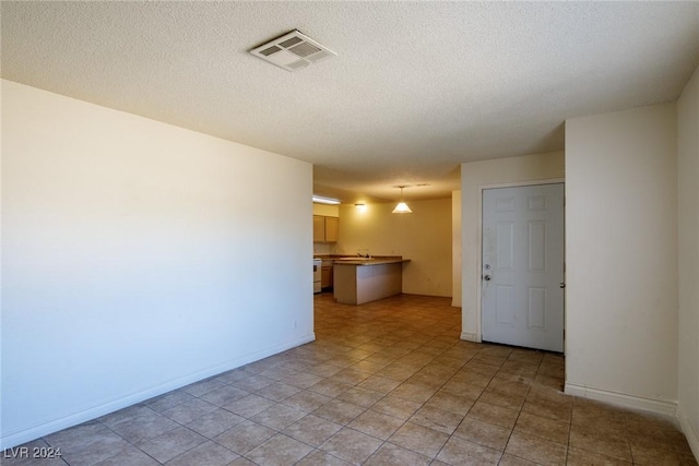 spare room with light tile patterned floors and a textured ceiling