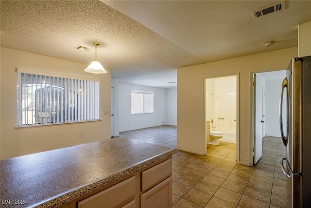 kitchen featuring stainless steel fridge, light tile patterned floors, pendant lighting, and a textured ceiling