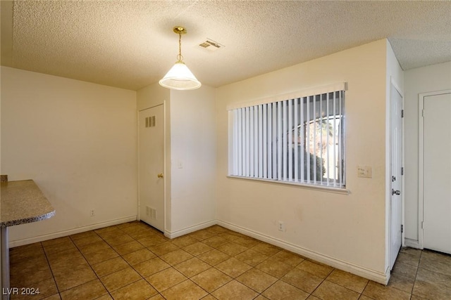 unfurnished dining area with light tile patterned floors and a textured ceiling