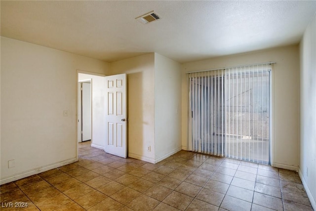 tiled spare room with a textured ceiling