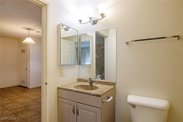 bathroom featuring vanity, tile patterned floors, a textured ceiling, and toilet