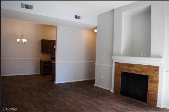 unfurnished living room featuring dark hardwood / wood-style flooring and a stone fireplace