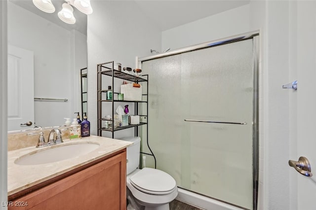 bathroom with hardwood / wood-style floors, vanity, a shower with shower door, and toilet