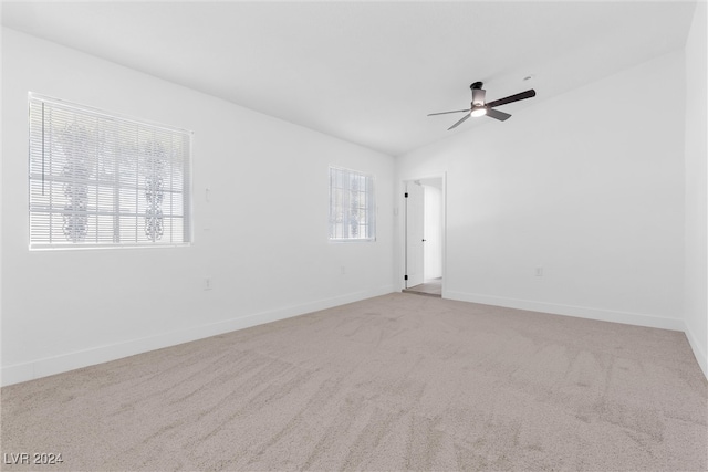 empty room featuring a wealth of natural light, light carpet, and ceiling fan