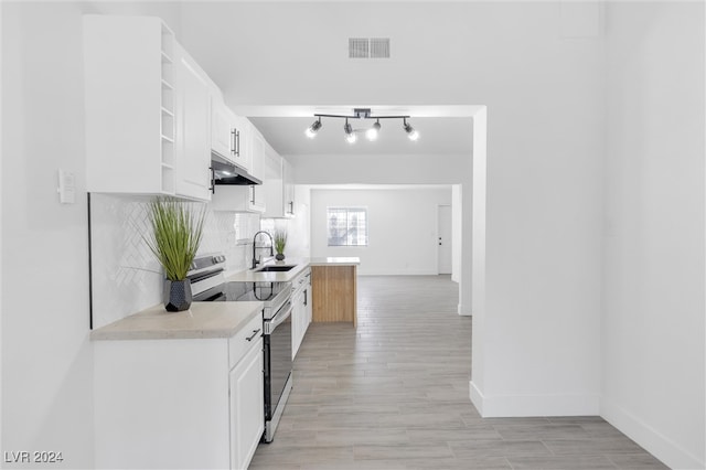 kitchen featuring sink, stainless steel range with electric stovetop, light hardwood / wood-style floors, and white cabinets