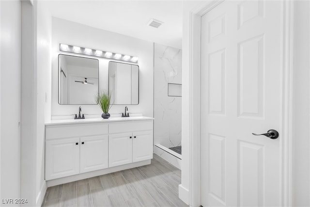 bathroom featuring hardwood / wood-style floors, vanity, and a tile shower