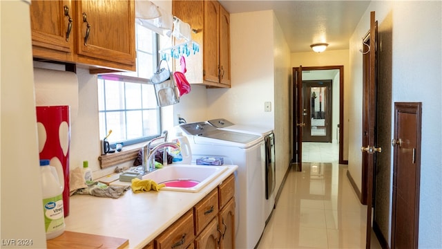 laundry room featuring cabinets, washing machine and dryer, light tile patterned floors, and sink