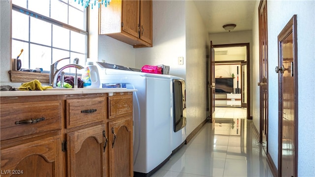 laundry area featuring cabinets, light tile patterned floors, and separate washer and dryer