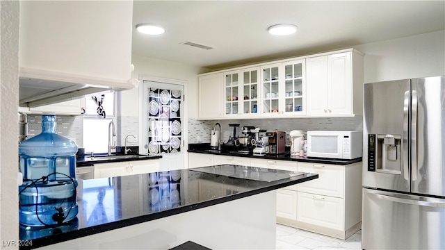 kitchen featuring stainless steel fridge, white cabinetry, sink, and tasteful backsplash