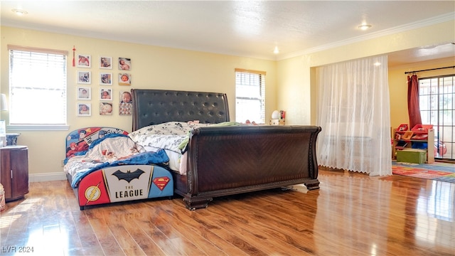 bedroom featuring hardwood / wood-style floors, multiple windows, and ornamental molding