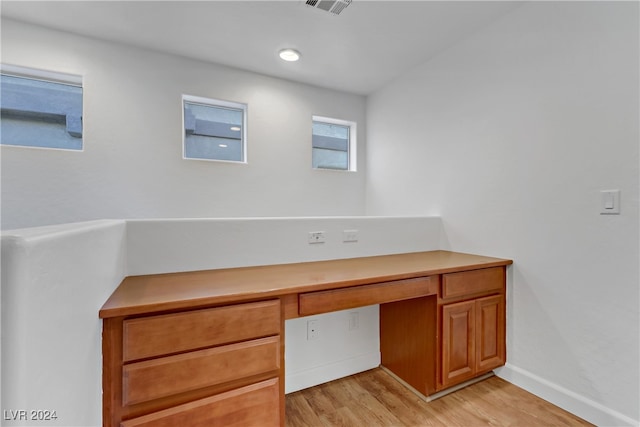 unfurnished office featuring built in desk and light wood-type flooring