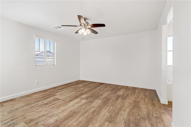 spare room featuring ceiling fan, light wood finished floors, and baseboards
