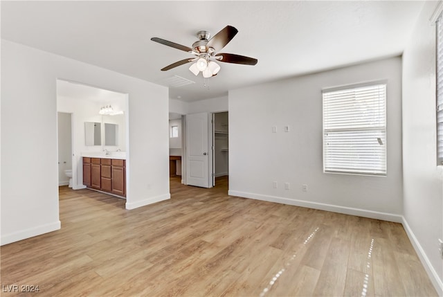 interior space with ensuite bathroom, ceiling fan, a spacious closet, light hardwood / wood-style flooring, and a closet