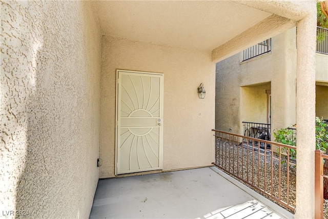 property entrance featuring stucco siding and a balcony