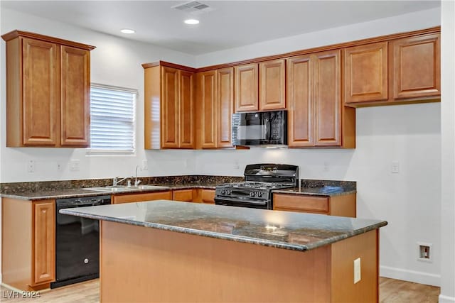 kitchen featuring black appliances, a sink, light wood-style floors, dark stone countertops, and recessed lighting