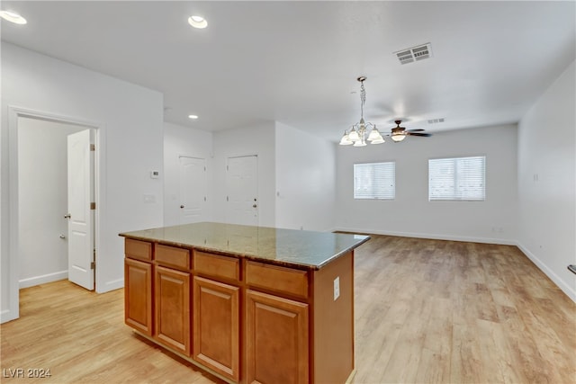 kitchen featuring ceiling fan with notable chandelier, light wood-type flooring, a kitchen island, and decorative light fixtures