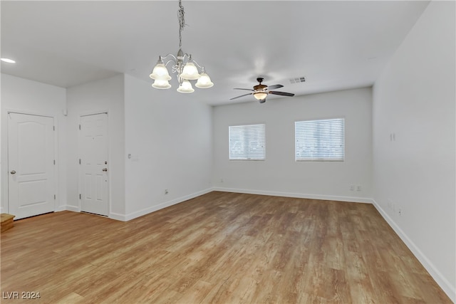 spare room with ceiling fan with notable chandelier and light hardwood / wood-style flooring