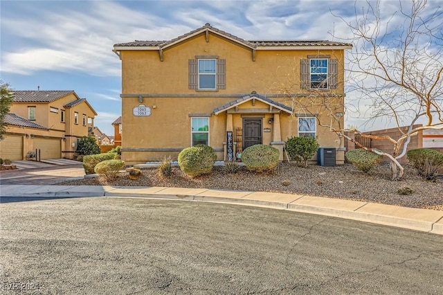 view of front of house featuring stucco siding, central AC, concrete driveway, a garage, and a tiled roof