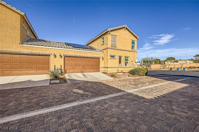 view of front of house featuring stucco siding, solar panels, and a tile roof