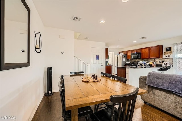 dining area featuring dark wood-style floors, visible vents, baseboards, recessed lighting, and stairs