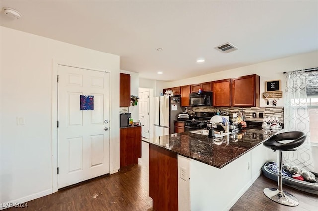 kitchen with visible vents, a peninsula, freestanding refrigerator, black microwave, and gas range