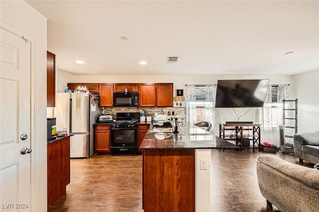 kitchen with visible vents, dark wood-type flooring, open floor plan, black appliances, and a sink