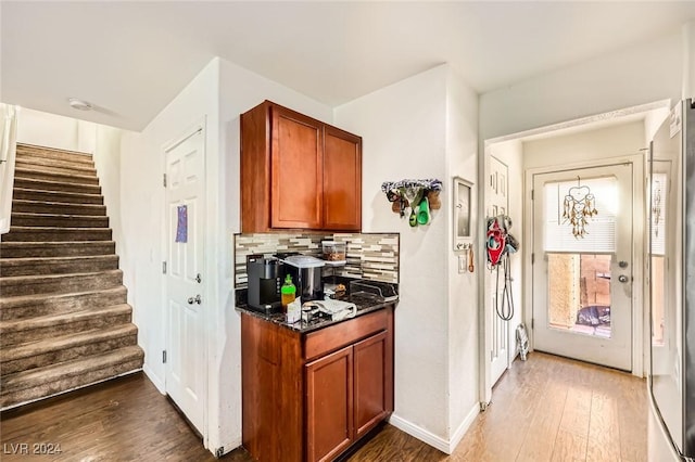 kitchen featuring tasteful backsplash, dark wood-style floors, brown cabinetry, and baseboards