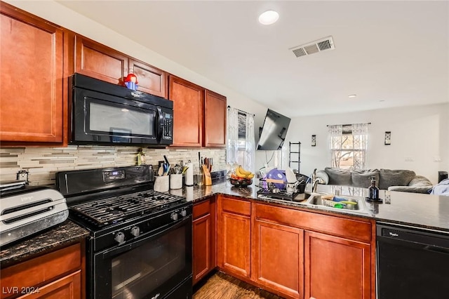 kitchen with visible vents, a sink, decorative backsplash, black appliances, and open floor plan