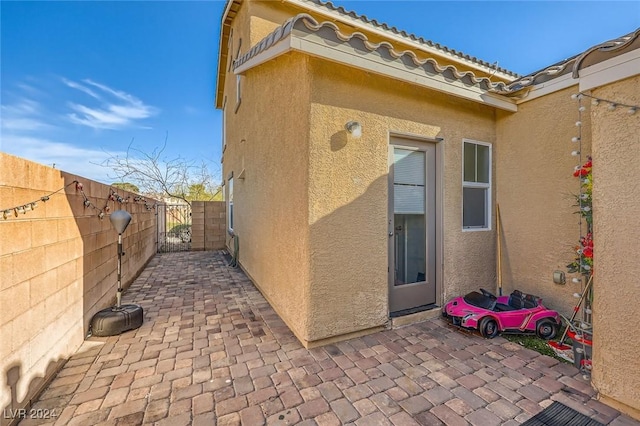 exterior space with stucco siding, a tile roof, a patio, and fence