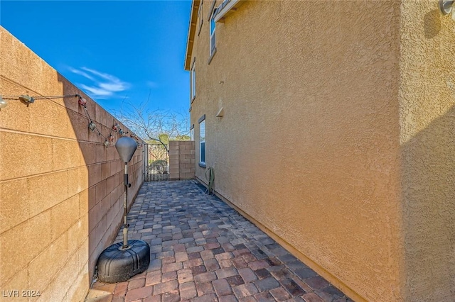 view of side of home with stucco siding, a patio, and fence