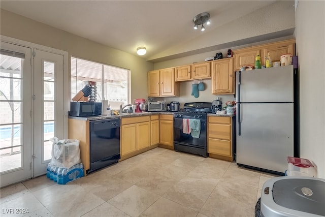 kitchen featuring light brown cabinets, black appliances, a healthy amount of sunlight, and vaulted ceiling