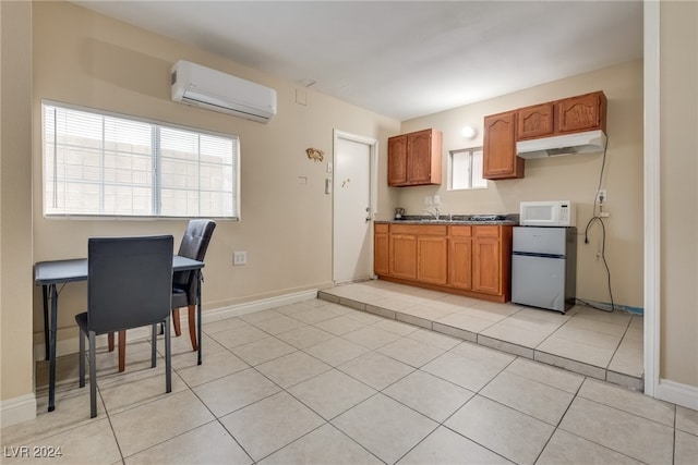 kitchen featuring a wall unit AC, fridge, light tile patterned floors, and sink