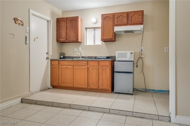 kitchen with white appliances, sink, and light tile patterned floors