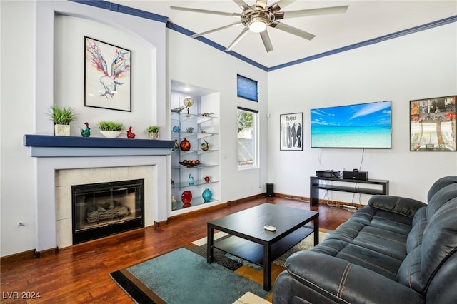 living room featuring built in features, crown molding, a fireplace, dark hardwood / wood-style floors, and ceiling fan