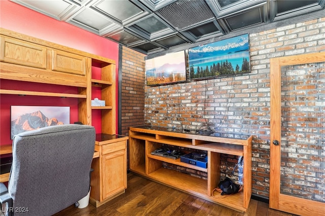 home office with coffered ceiling, dark hardwood / wood-style floors, and brick wall