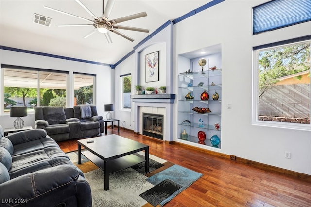 living room featuring a tile fireplace, a wealth of natural light, hardwood / wood-style floors, and vaulted ceiling