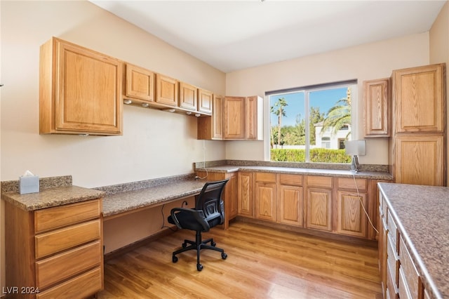 home office featuring light wood-type flooring and built in desk