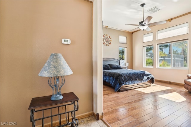 bedroom with light hardwood / wood-style flooring, ceiling fan, and crown molding