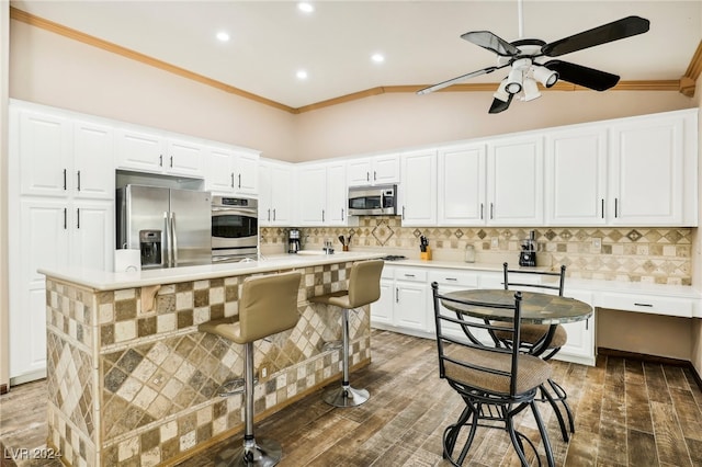 kitchen with ornamental molding, appliances with stainless steel finishes, a center island, and dark hardwood / wood-style flooring