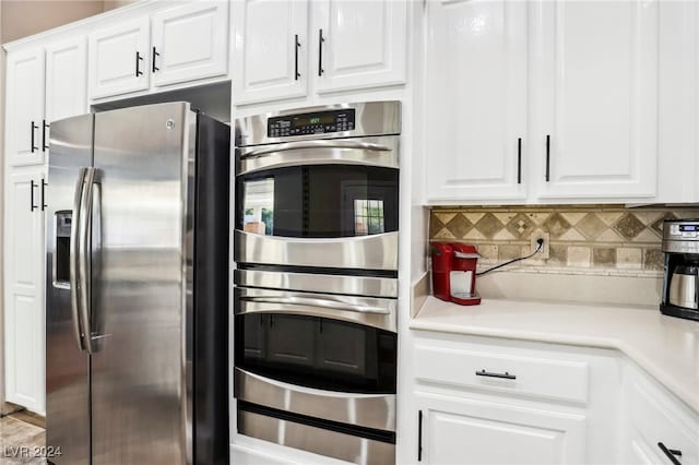 kitchen with white cabinets, backsplash, and appliances with stainless steel finishes