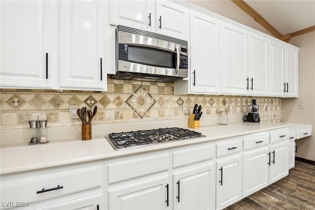 kitchen featuring crown molding, white cabinetry, appliances with stainless steel finishes, dark hardwood / wood-style floors, and decorative backsplash