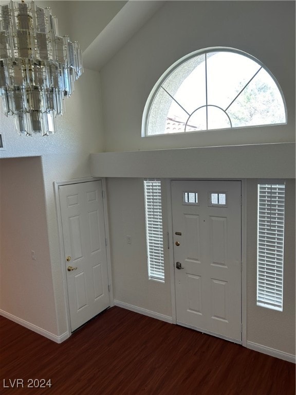 foyer entrance featuring a towering ceiling, a healthy amount of sunlight, dark hardwood / wood-style flooring, and a notable chandelier