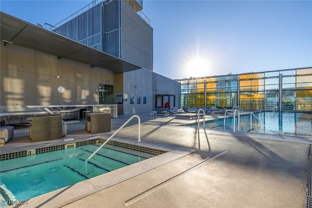 view of swimming pool featuring a hot tub and a patio area