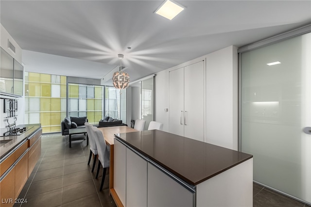 kitchen with white cabinetry, a notable chandelier, dark tile patterned flooring, and a center island